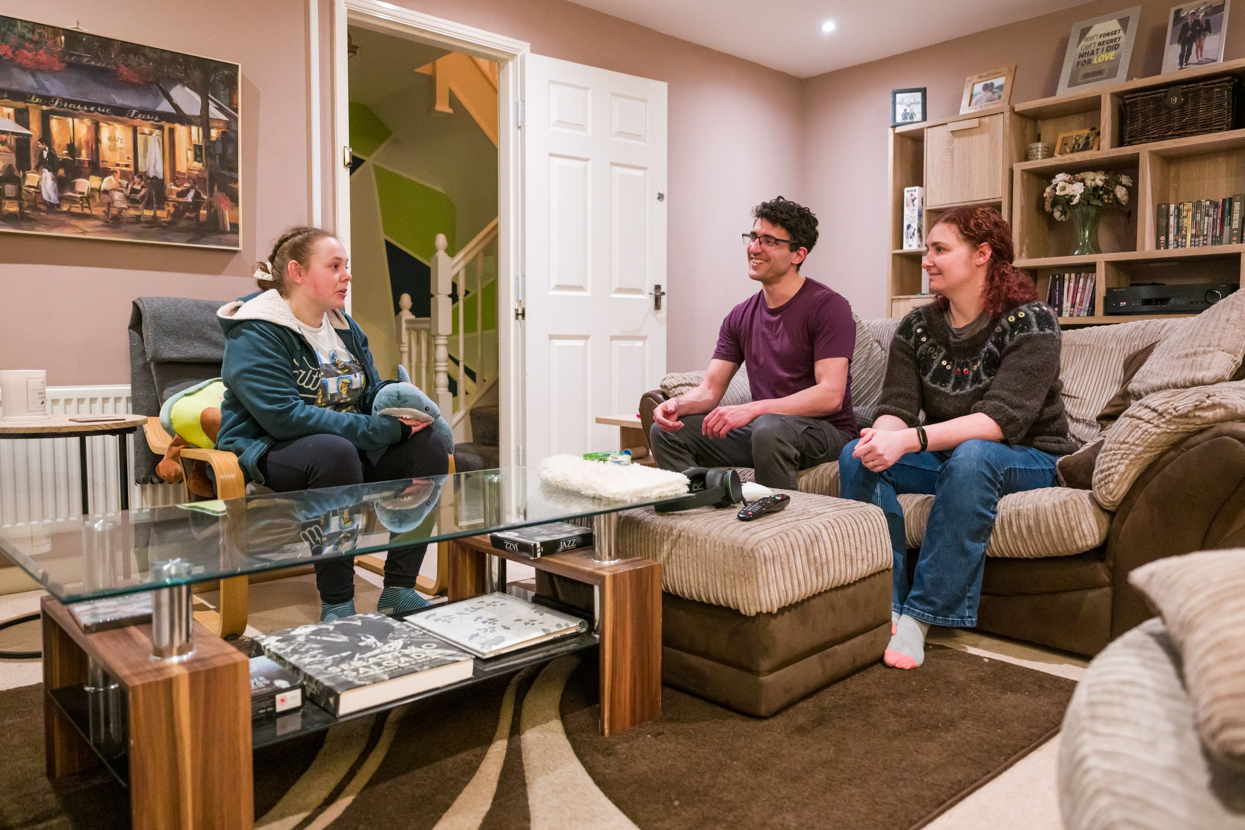 Open Homes Nottingham volunteers having a conversation with a young woman in a comfortable living room, supporting homeless youth