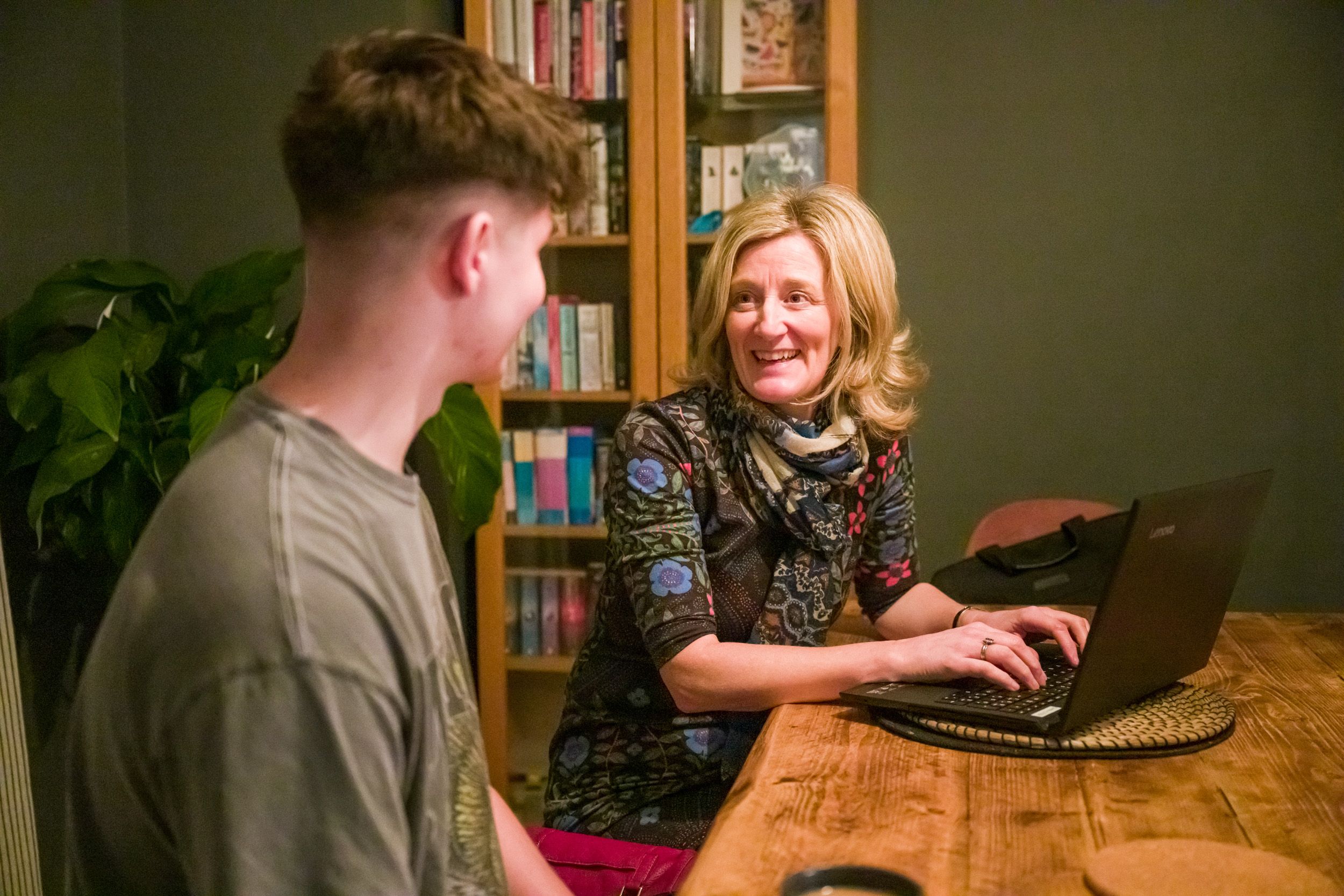 Open Homes Nottingham volunteer mentoring a young man at a kitchen table with a laptop, supporting homeless youth